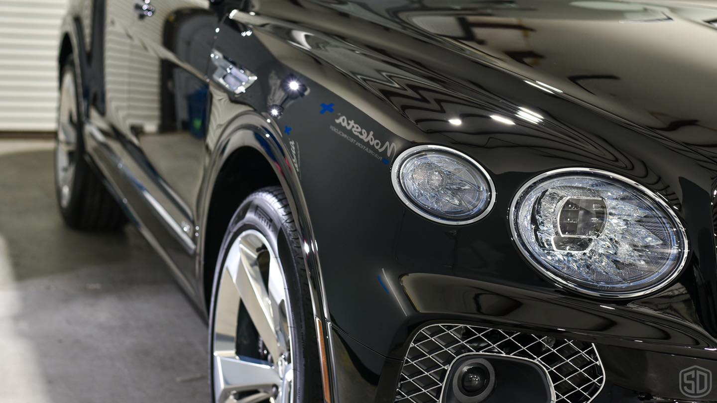 A black bentley is parked in a garage.