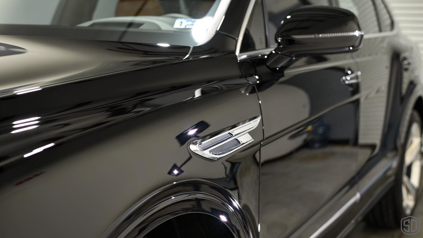 A close up of a black car parked in a garage.