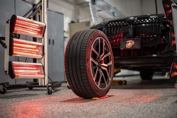 A car wheel is sitting on the ground in a garage next to a heater.