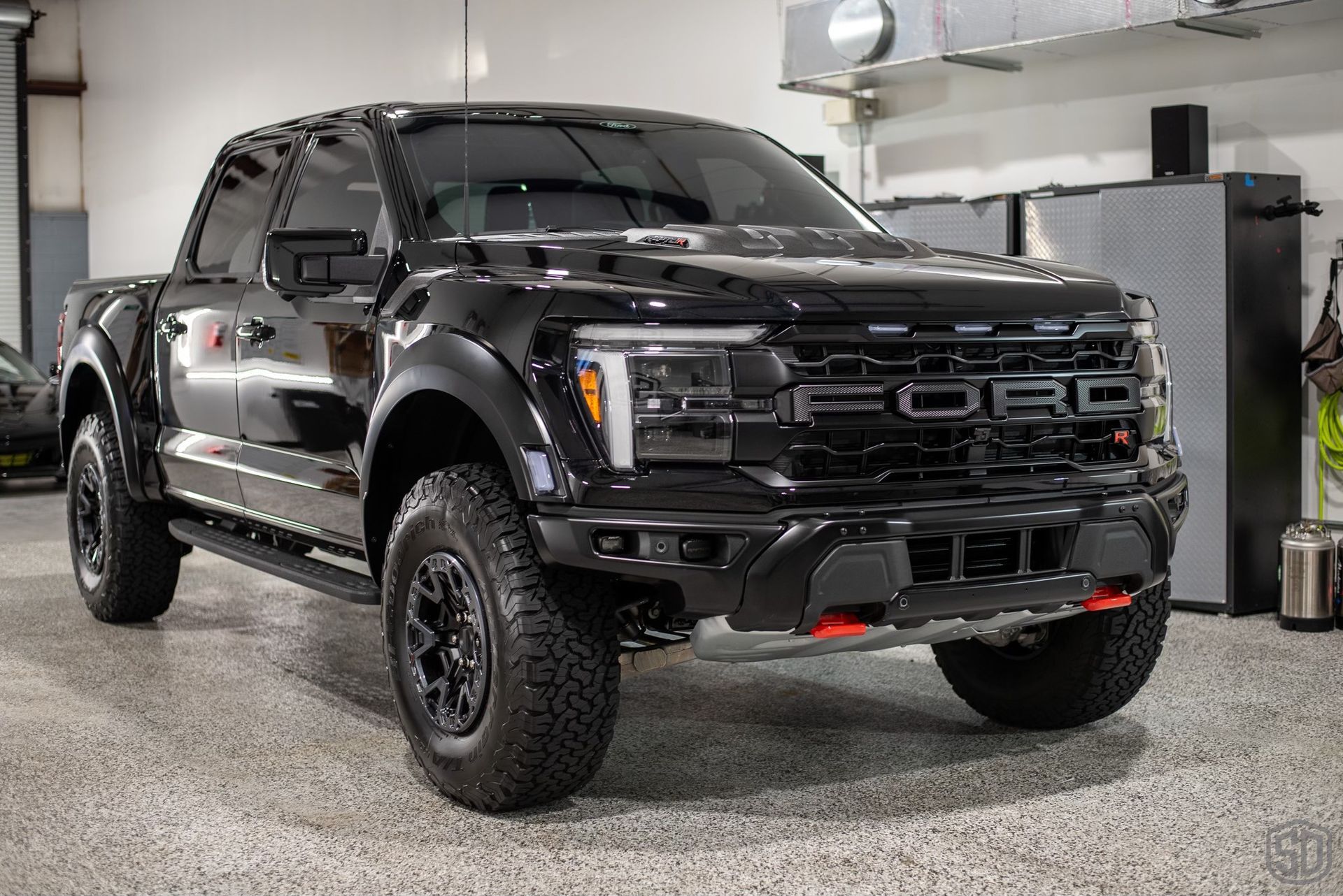 A black ford raptor is parked in a garage.