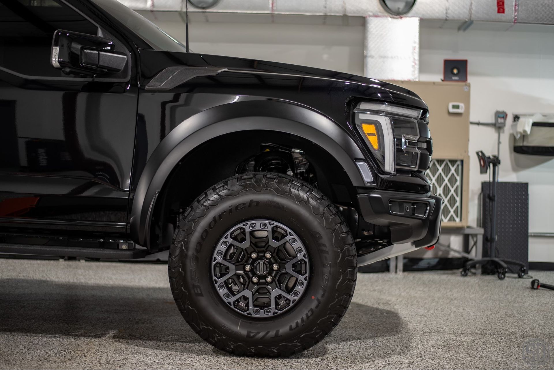 A black ford raptor is parked in a garage.