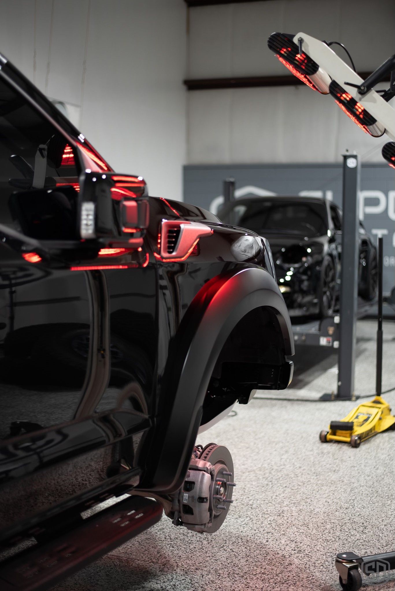 A black truck is being worked on in a garage.