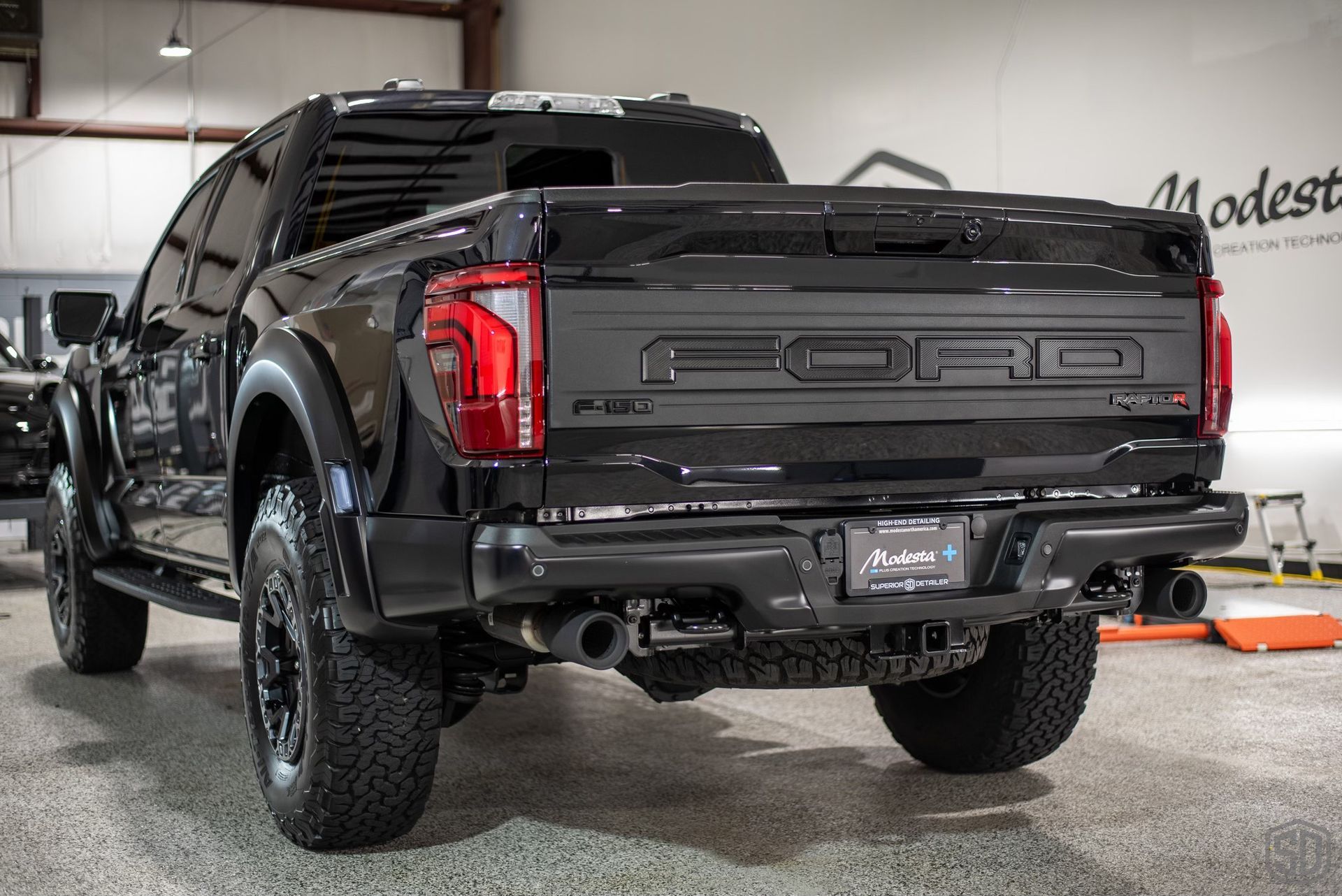 A black ford raptor truck is parked in a garage.