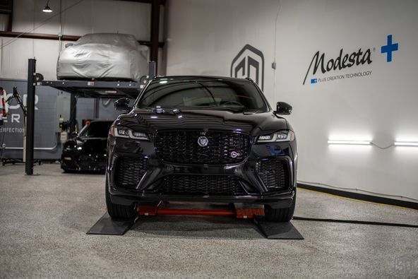 A black car is sitting on a lift in a garage.