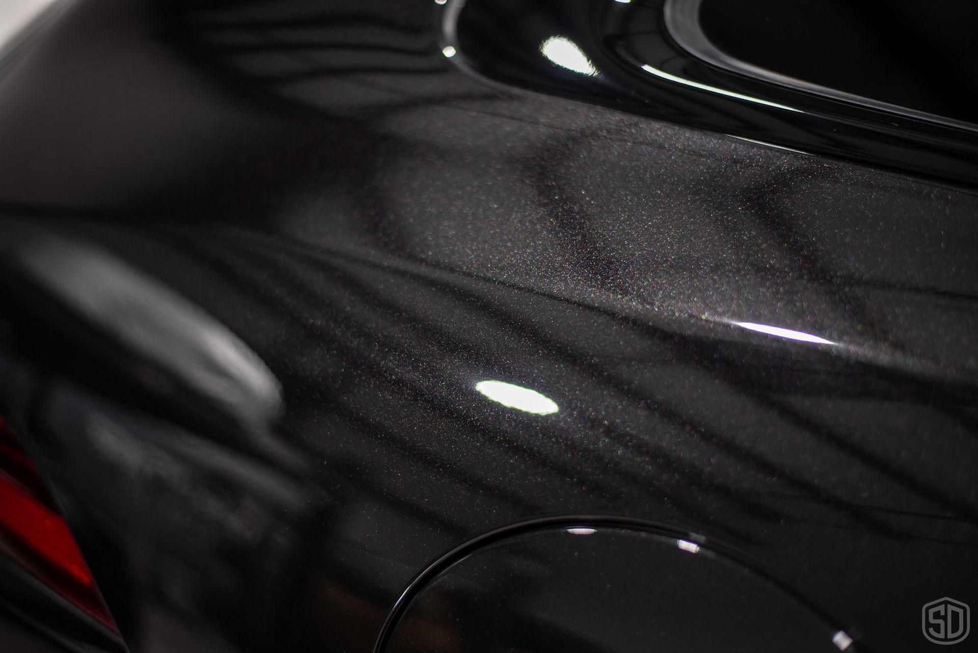 A close up of a black car with a lot of scratches on it.