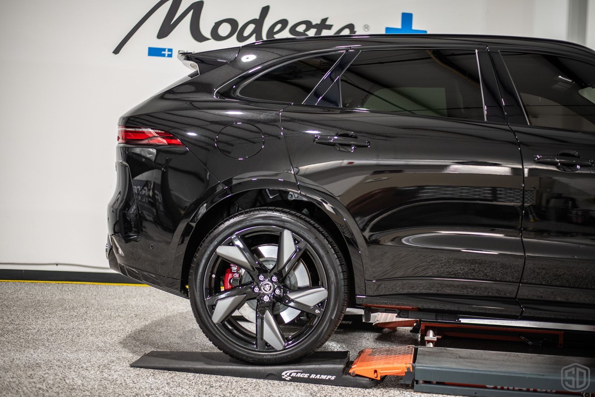 A black car is sitting on a lift in a garage.