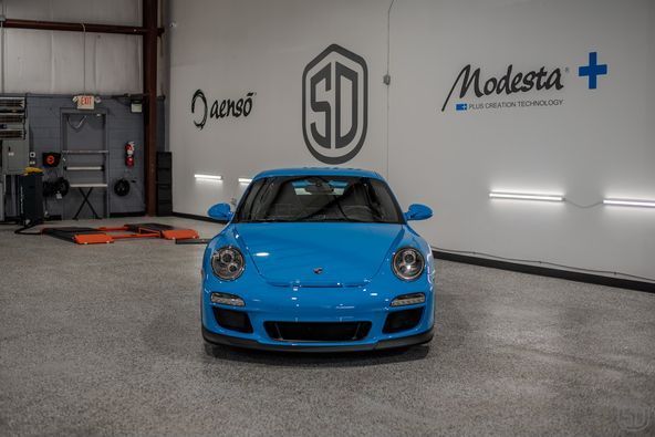 A blue porsche 911 gt3 is parked in a garage.