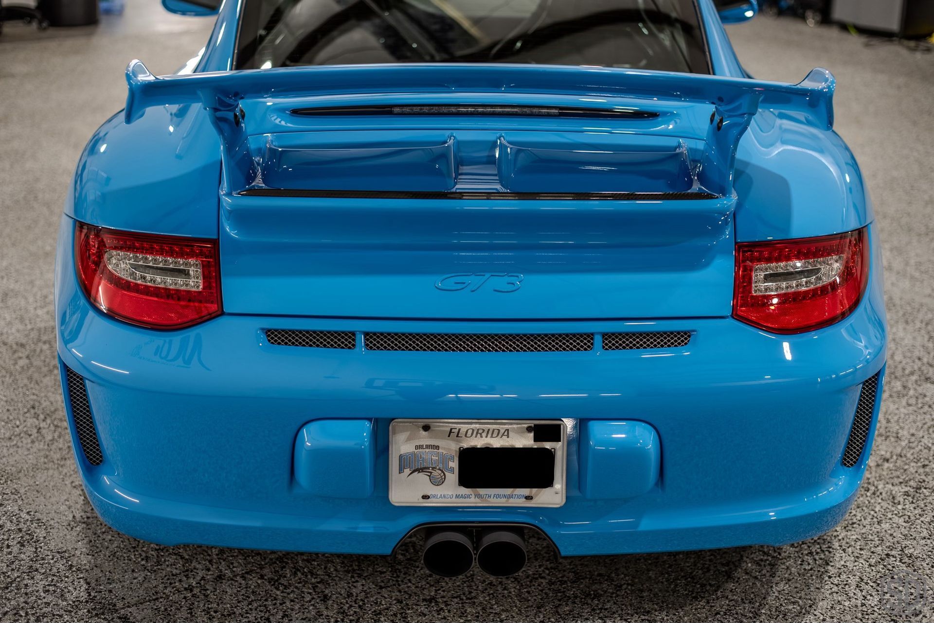 A blue porsche 911 gt3 is parked in a garage.