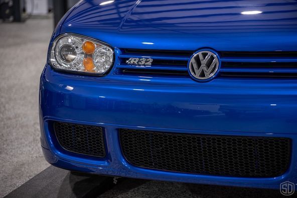 A close up of the front of a blue volkswagen golf r32.