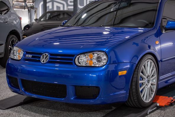 A blue volkswagen golf r32 is parked in a garage.