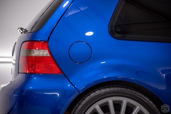 A blue car with a red tail light is parked in a garage.