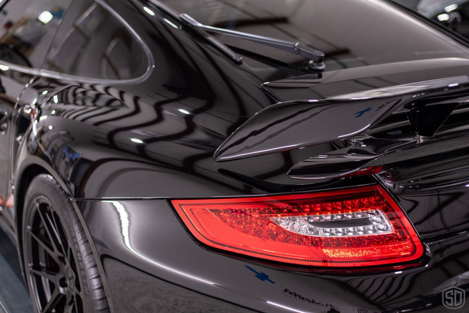 A black porsche 911 turbo s is parked in a garage.