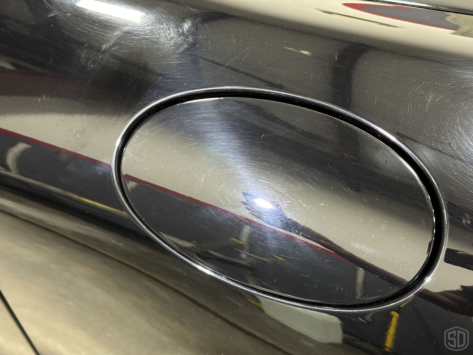 A close up of a gas cap on a car, highlighting the scratches and damage to the paint