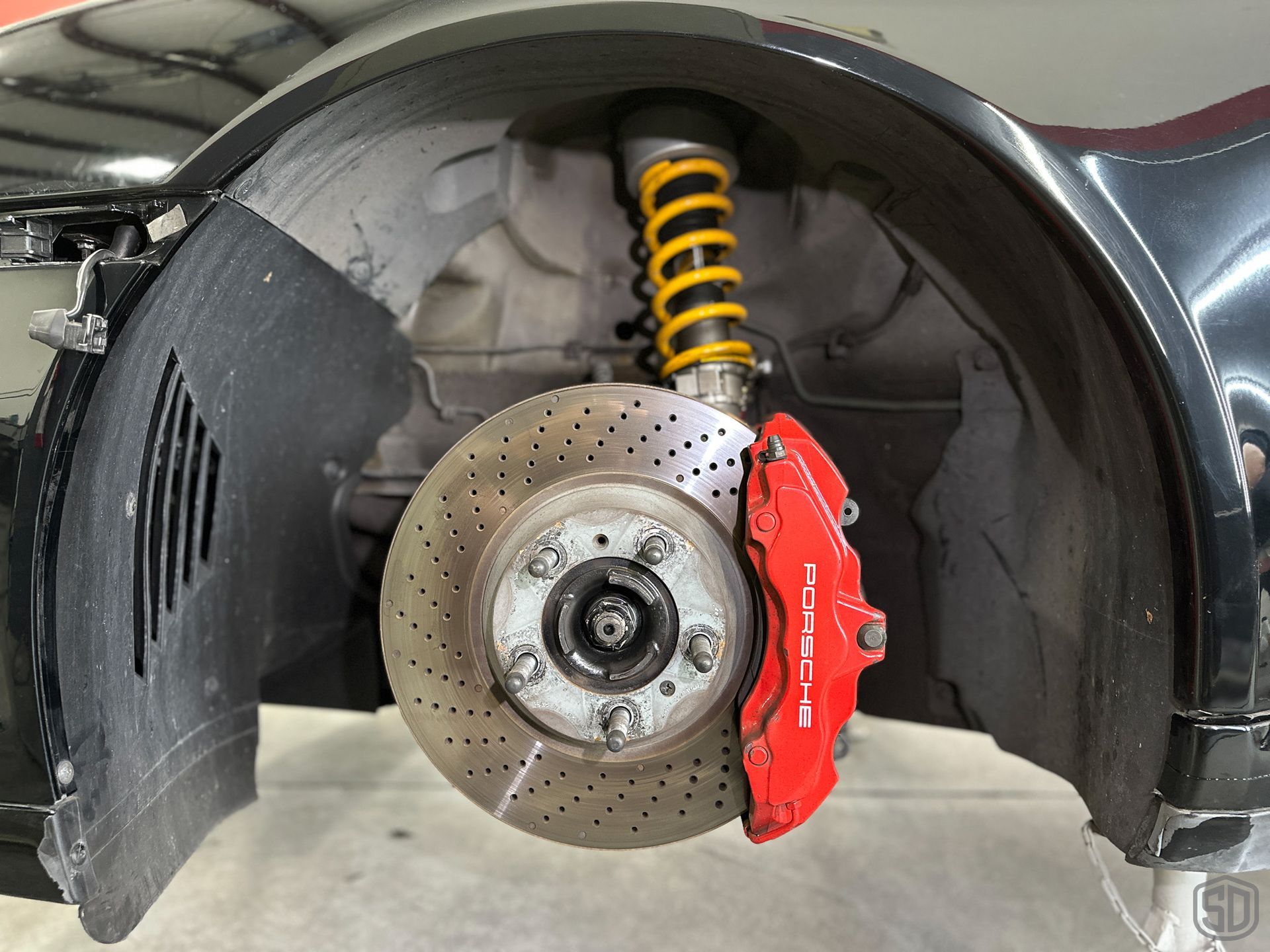 A close up of a car 's front brake and shock absorber