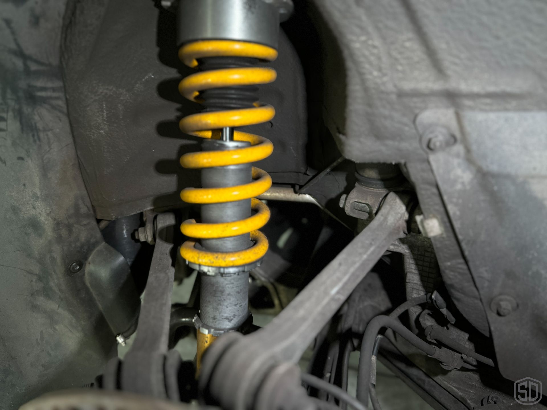 A close up of a shock absorber on a car with yellow springs.