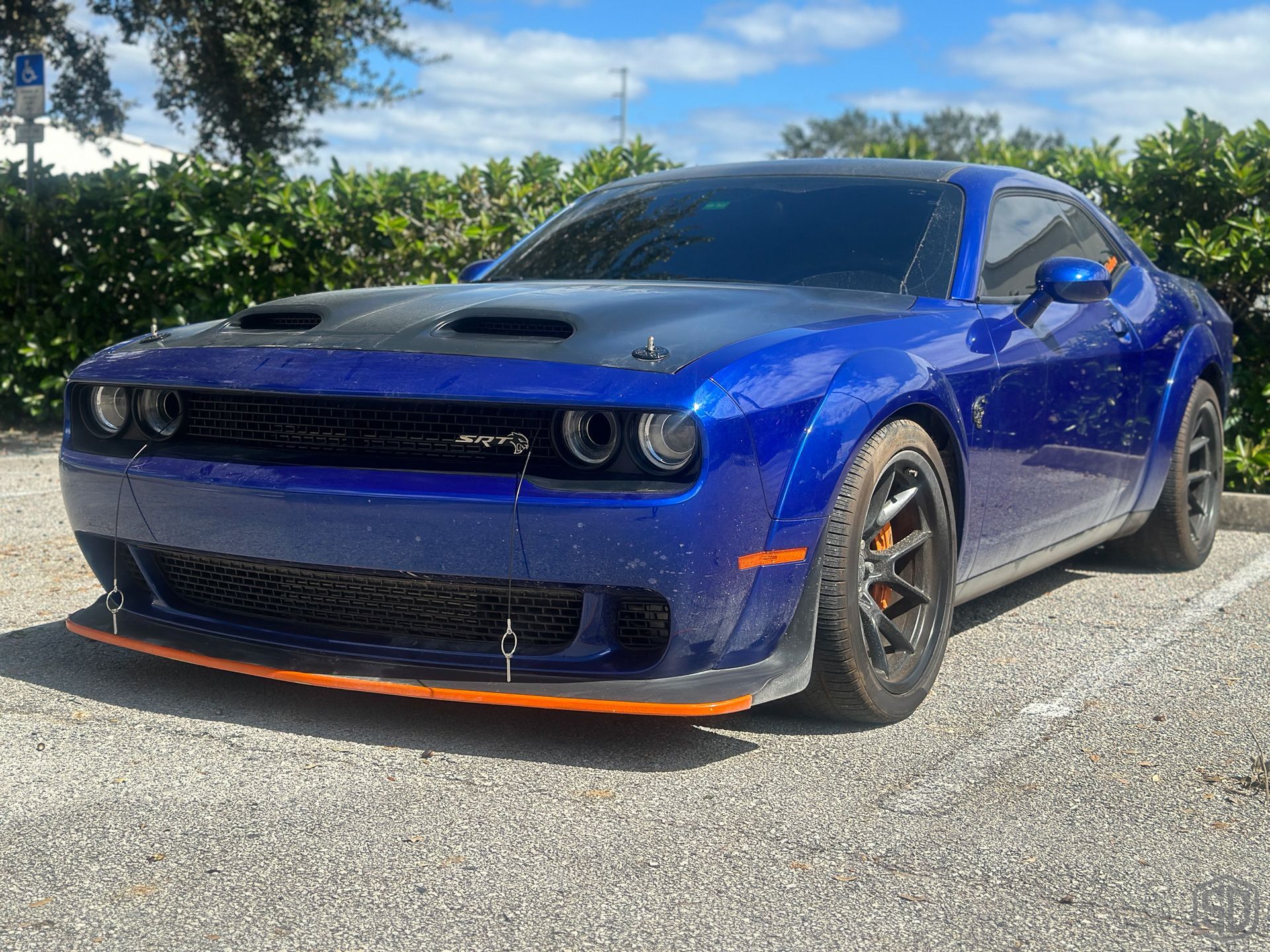 A blue dodge challenger is parked in a parking lot.