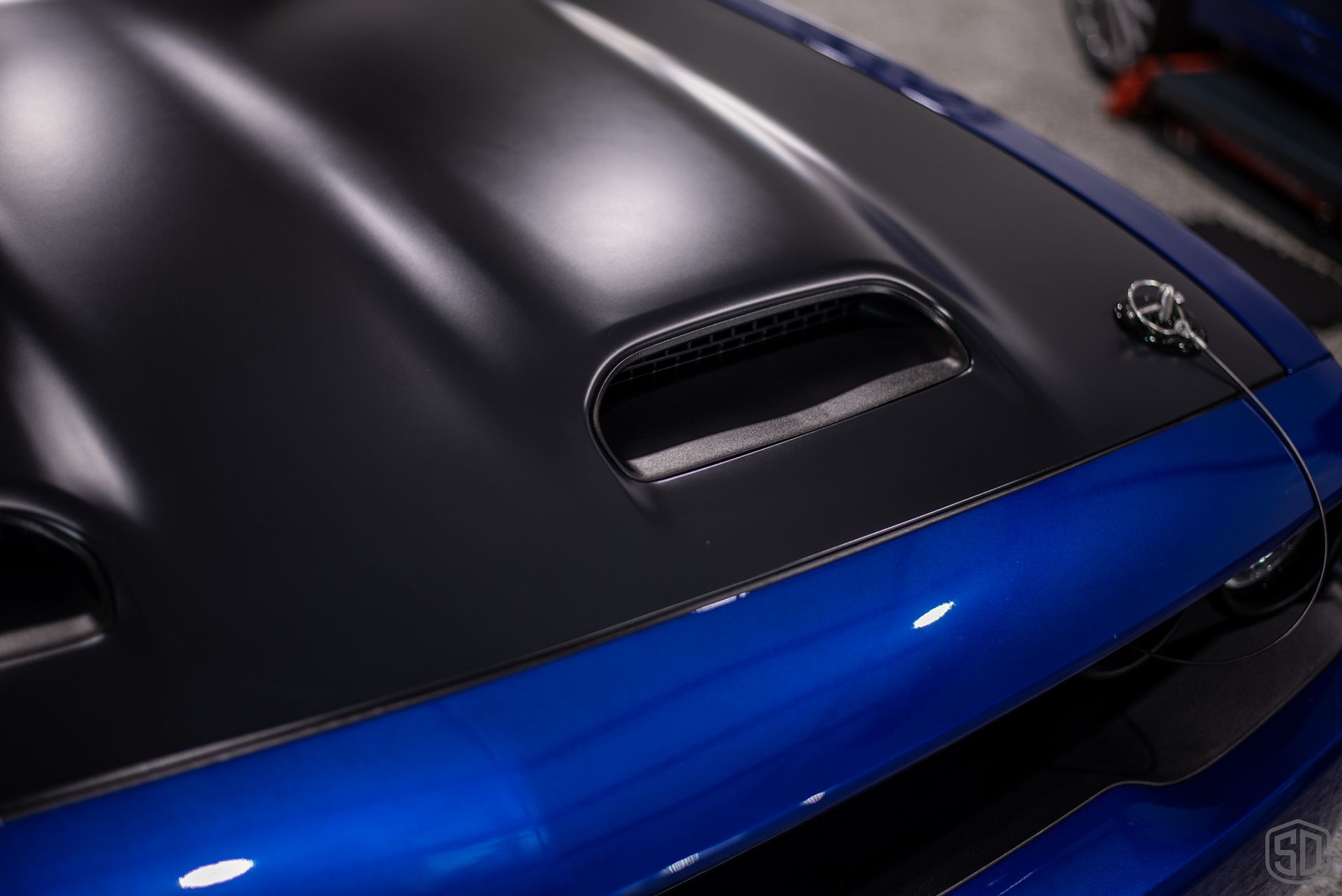 A close up of a blue car with a black hood