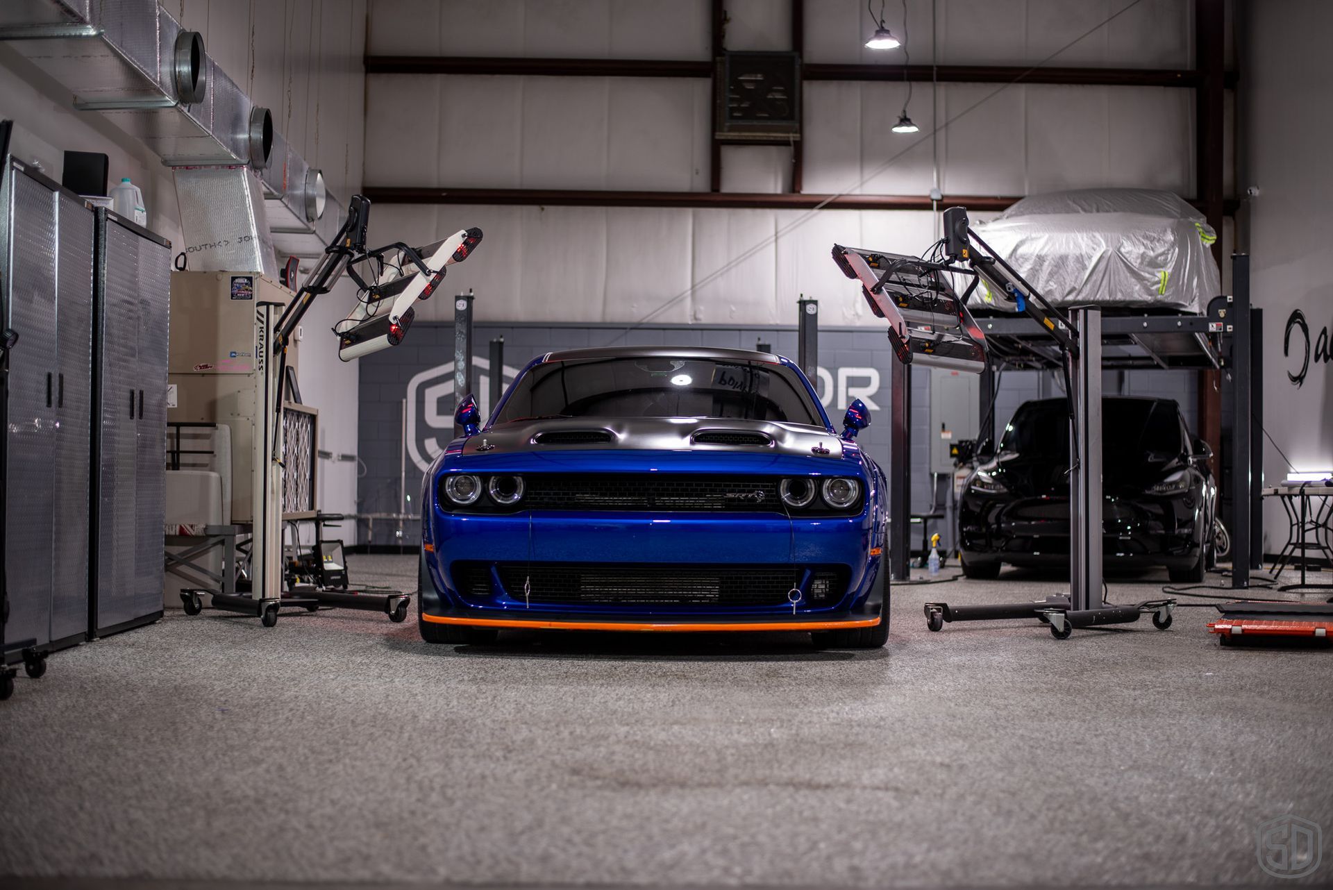 A blue dodge challenger is parked in a garage.