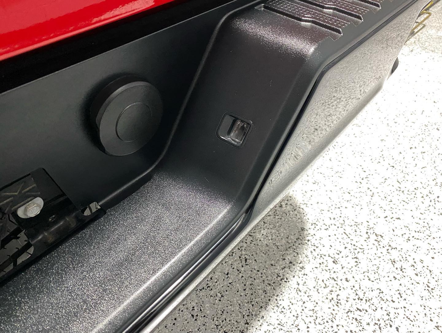 A red truck is parked in a garage with a black bumper.