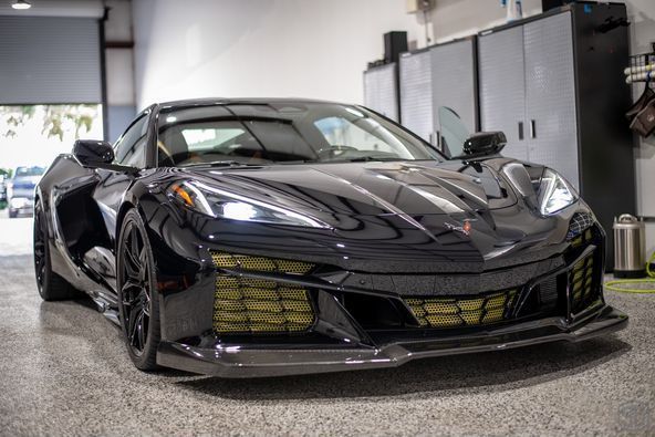 A black corvette is parked in a garage.