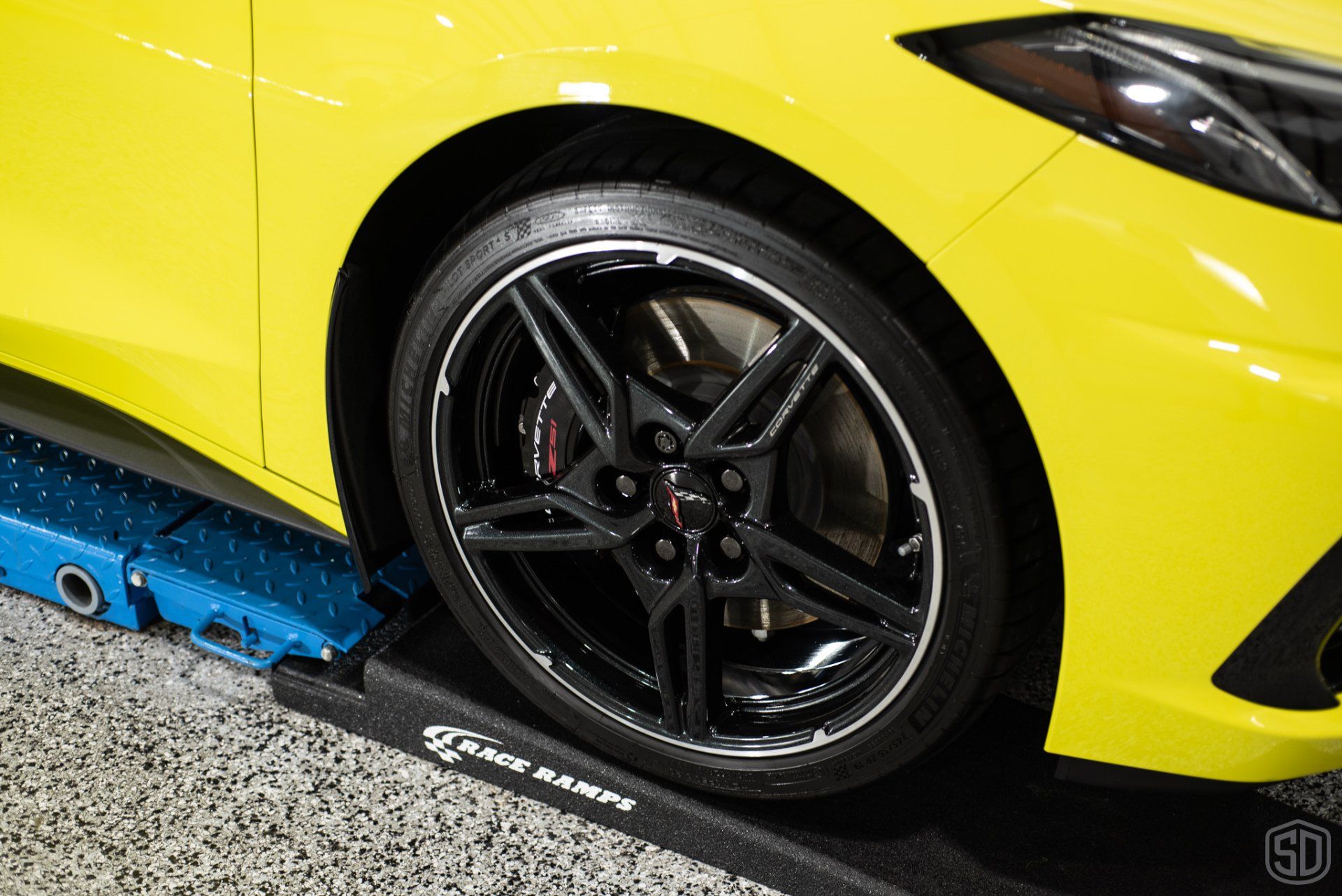 A yellow sports car is parked on a ramp in a garage.