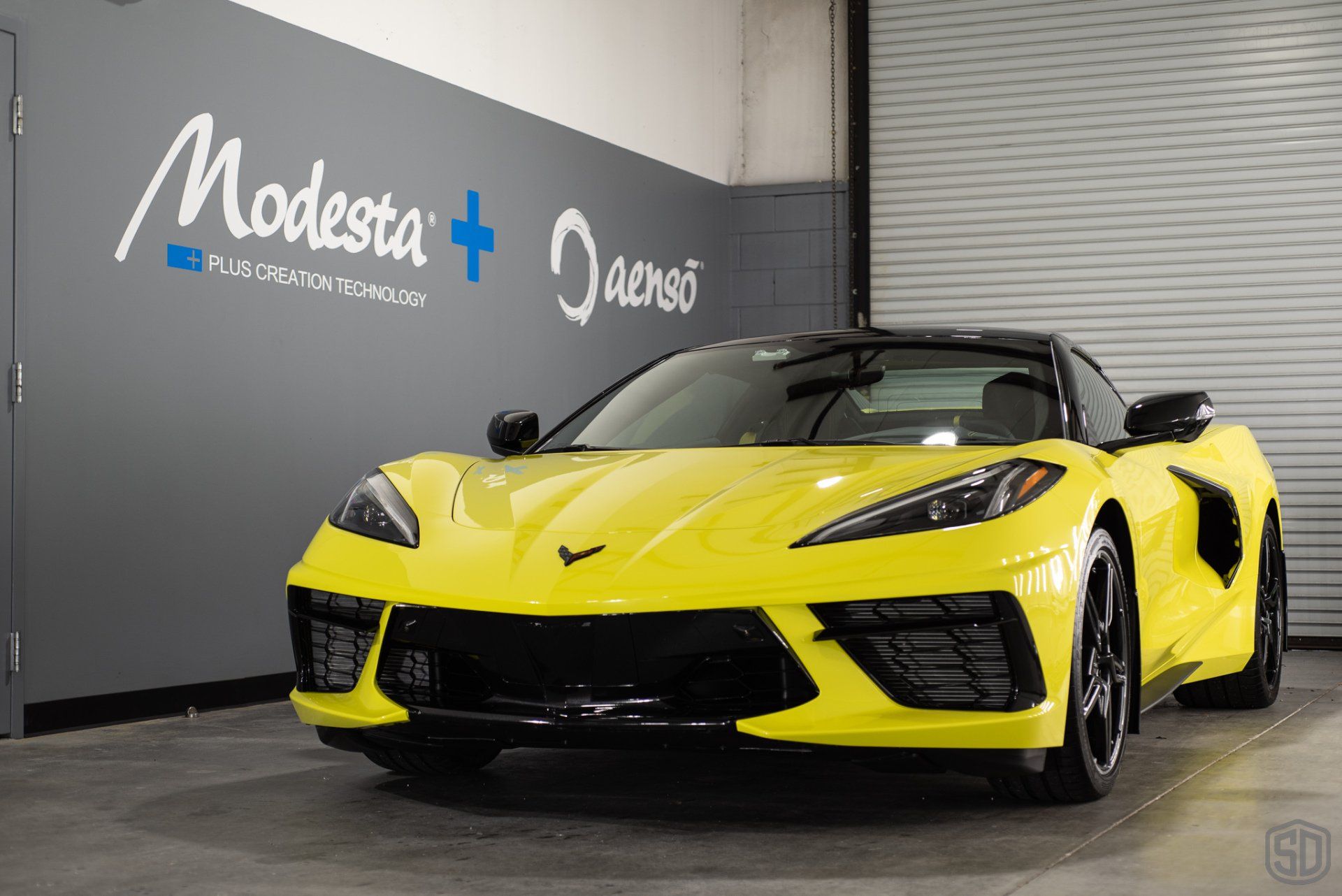 A yellow corvette convertible is parked in a garage.