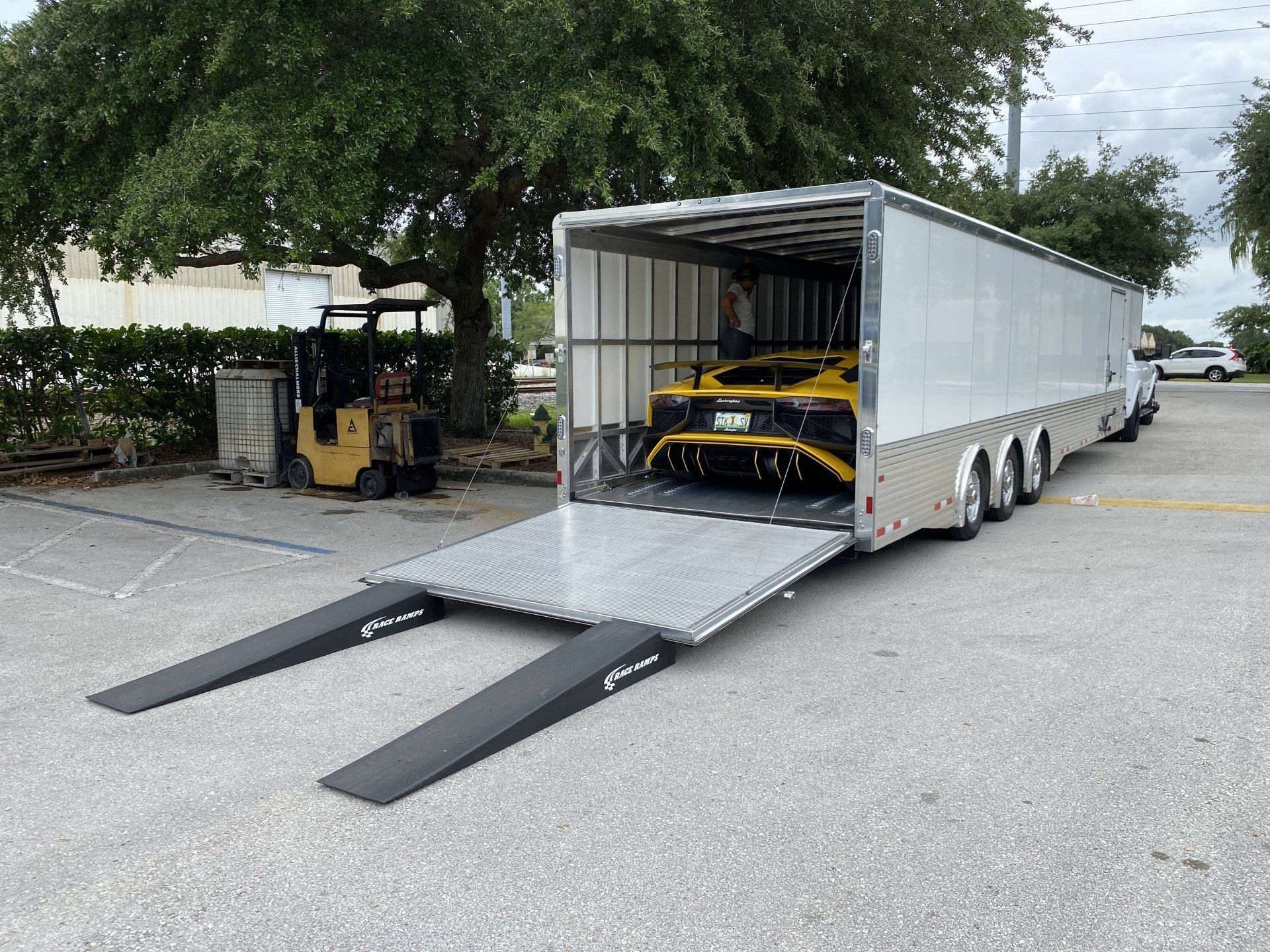 A car is being transported on a trailer in a parking lot.