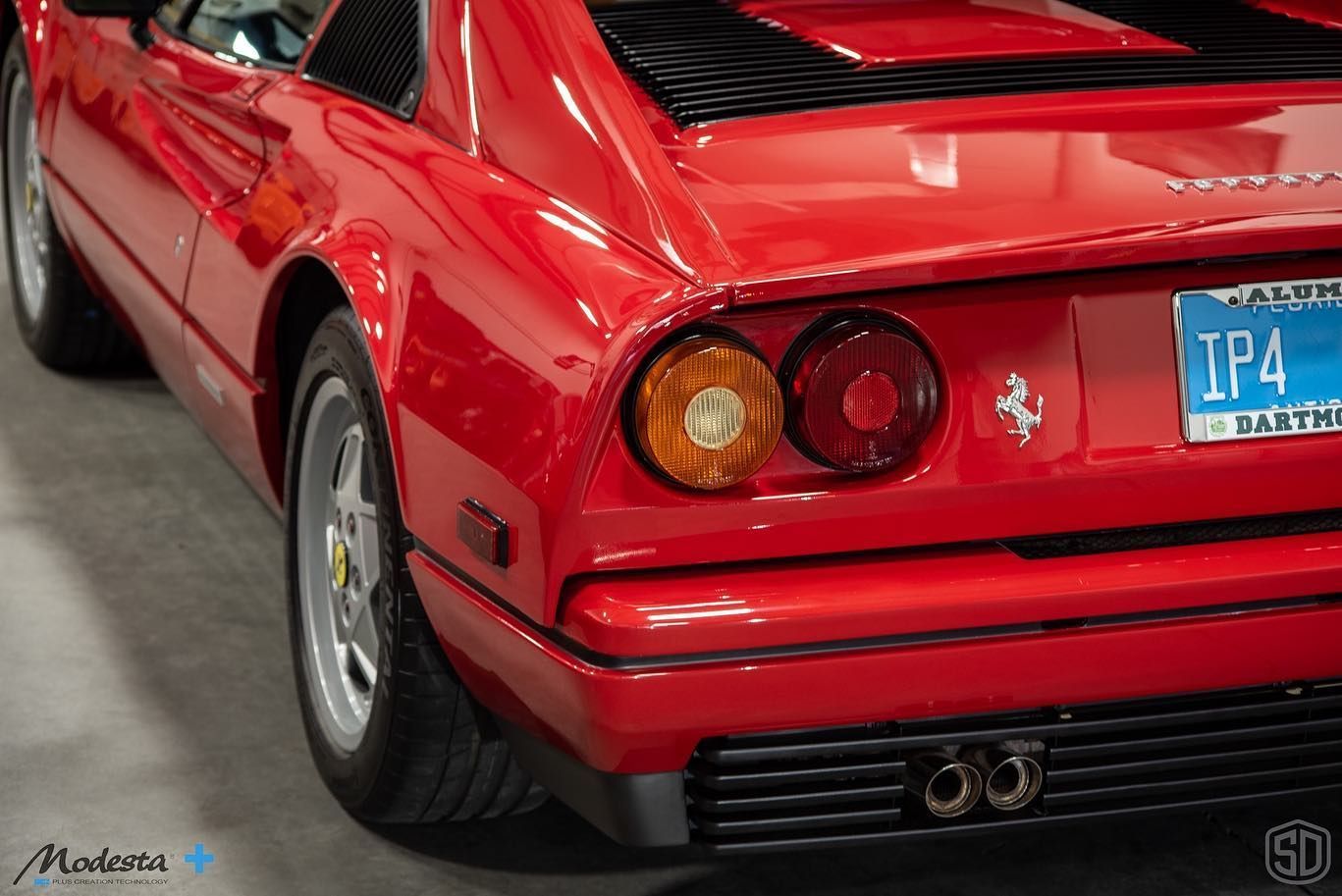 A red ferrari with a license plate that says ip4