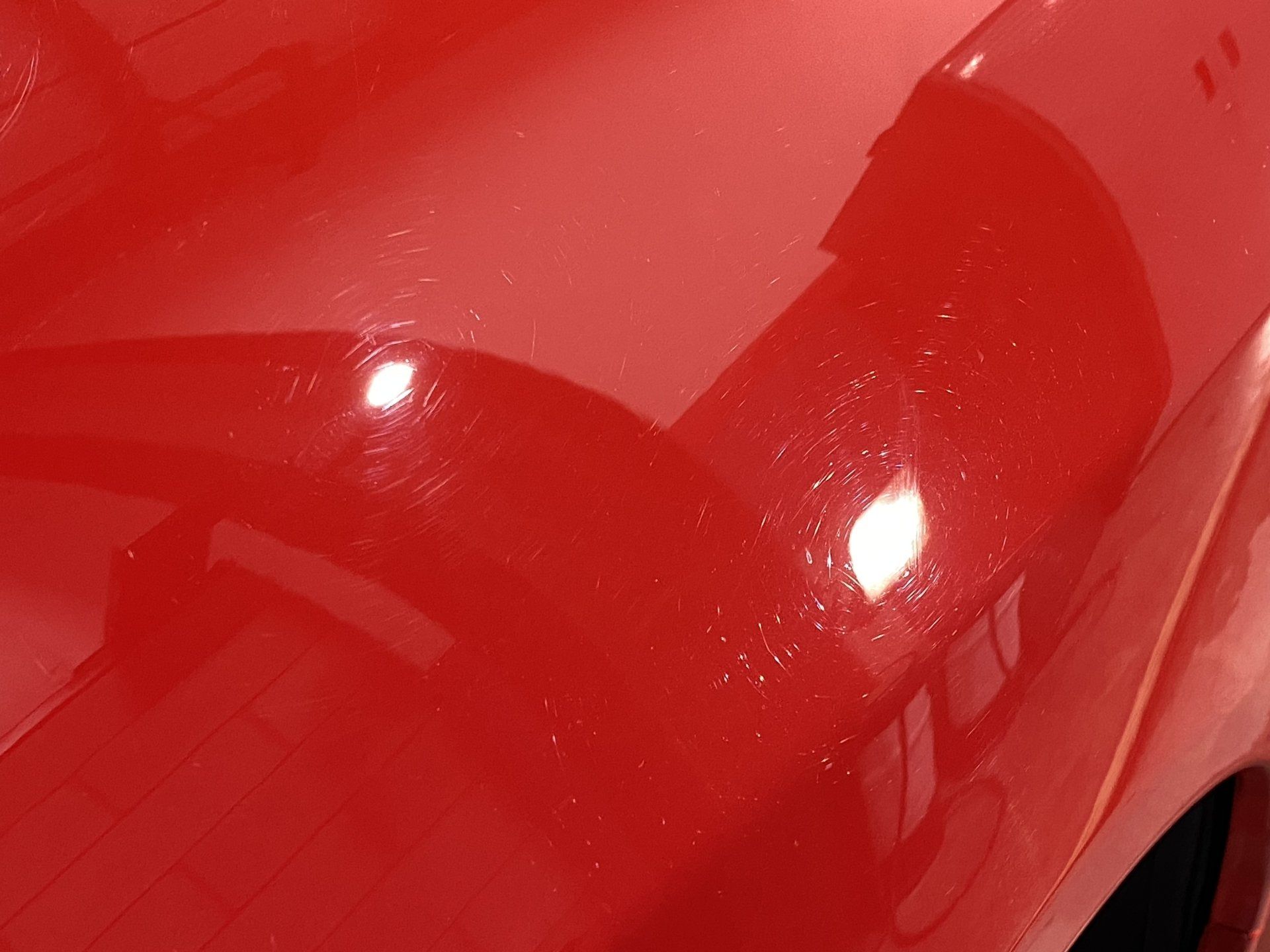 A close up of a red car 's hood in a garage.