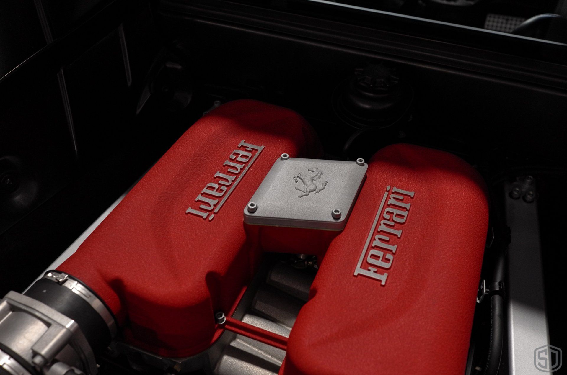 A close up of a ferrari engine with red covers