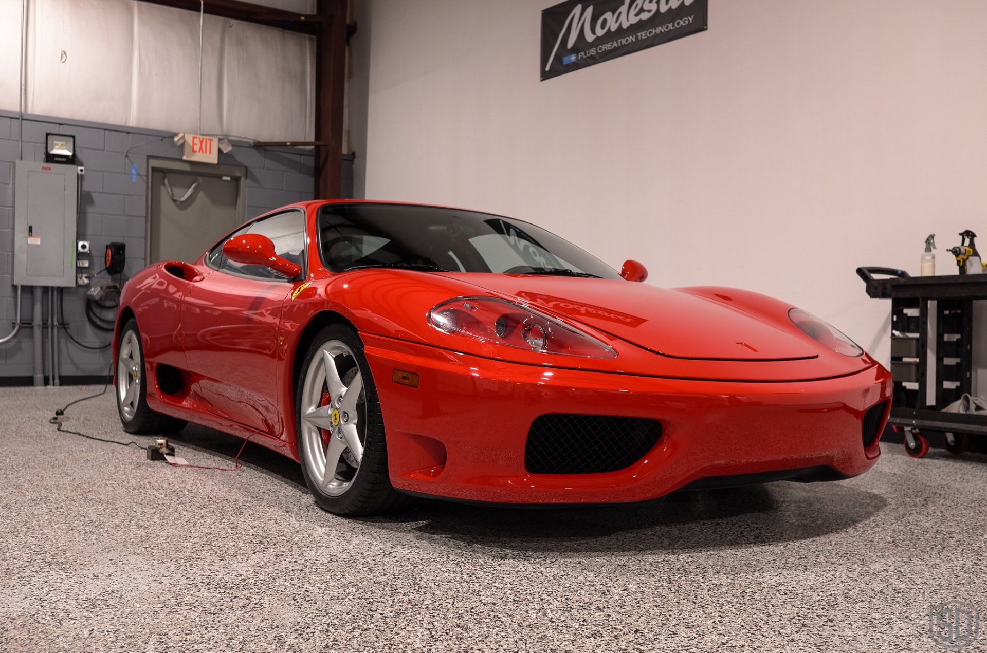 A red ferrari sports car is parked in a garage.