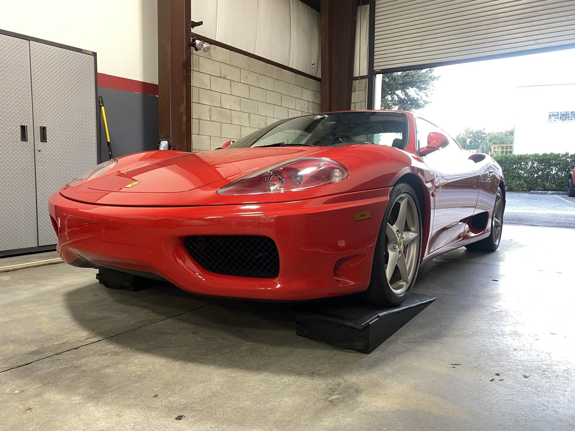A red sports car is parked on a ramp in a garage.