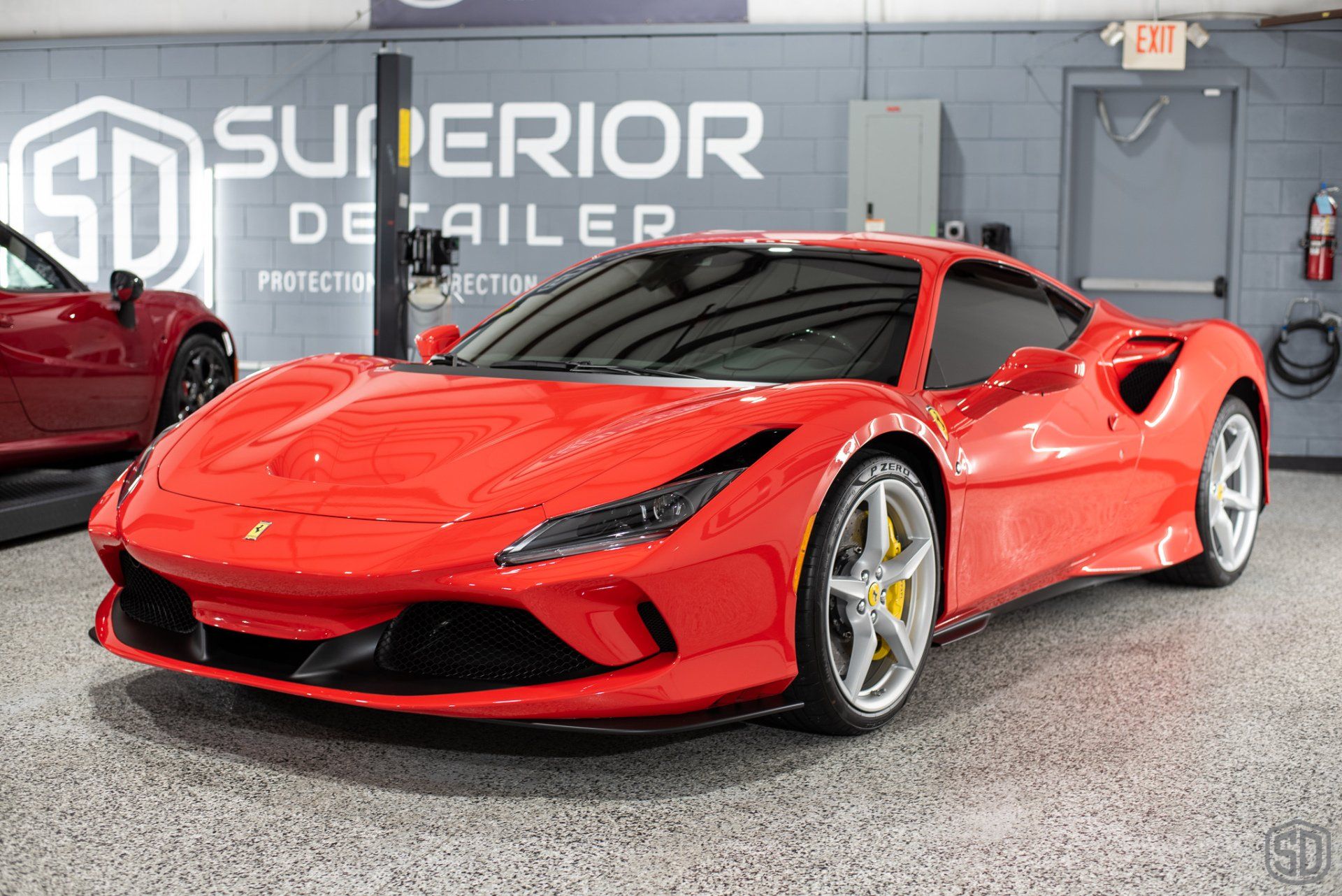 A red ferrari f8 spider is parked in a garage.