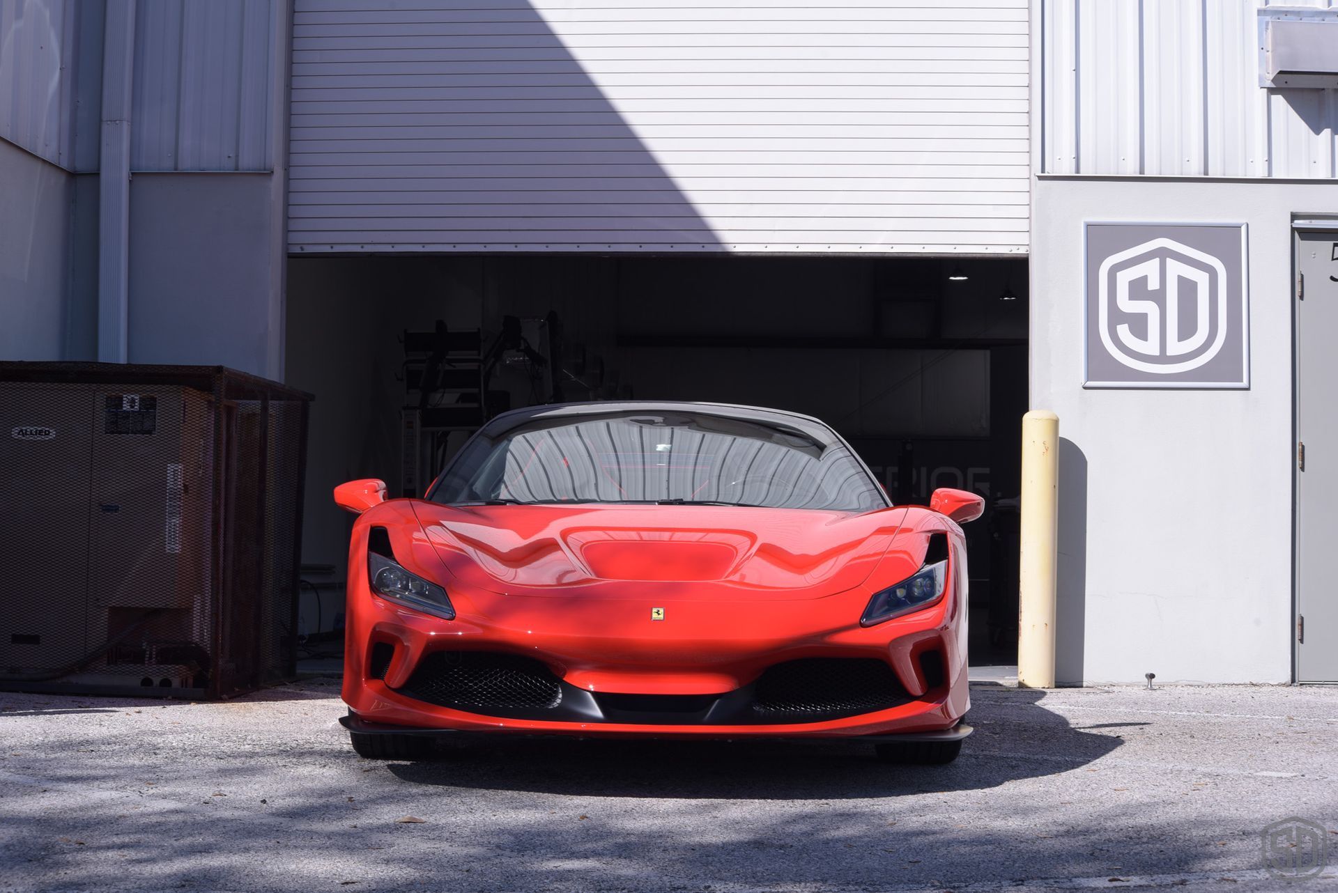 A red sports car is parked in front of a garage door.