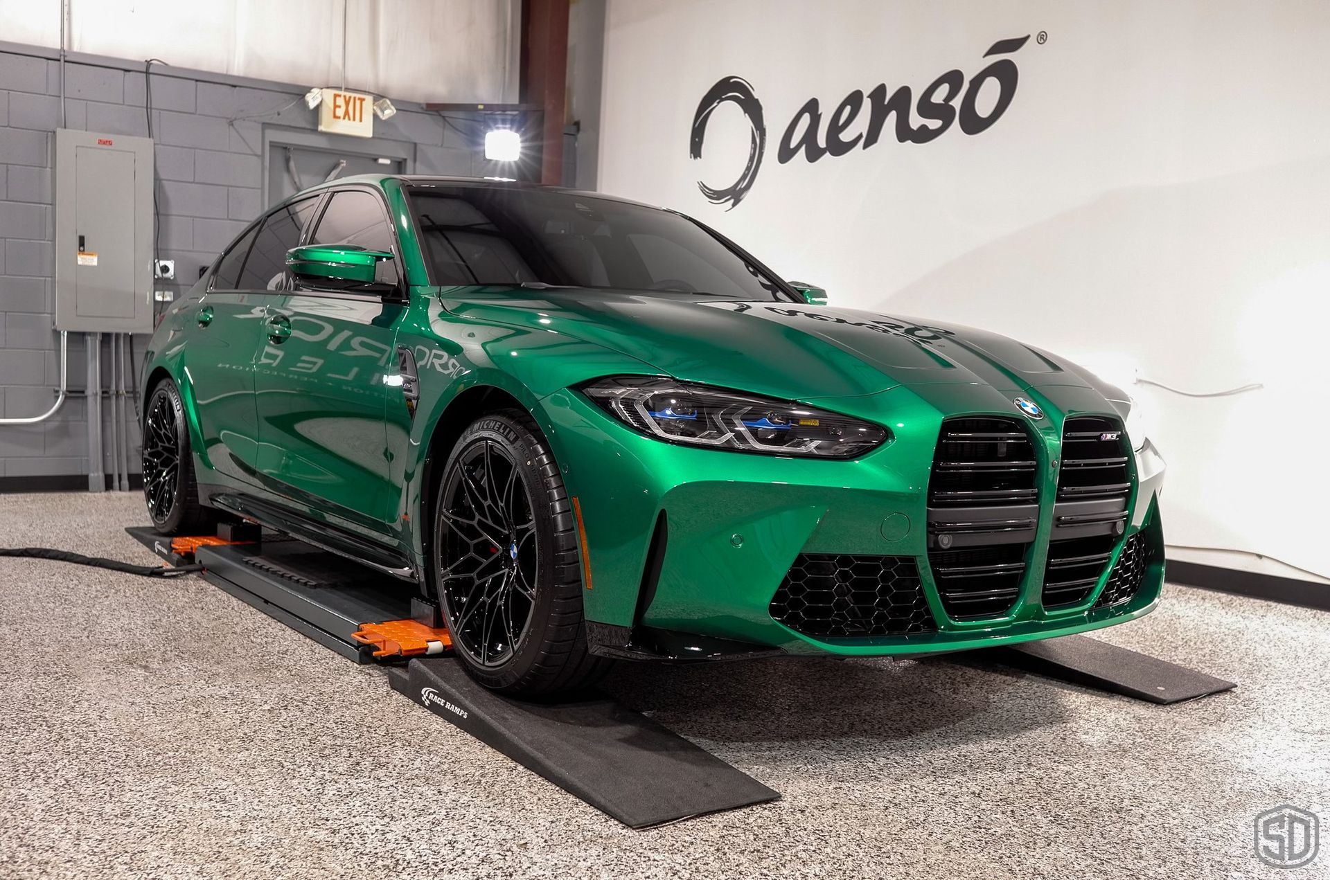 A green bmw m3 is sitting on a ramp in a garage.