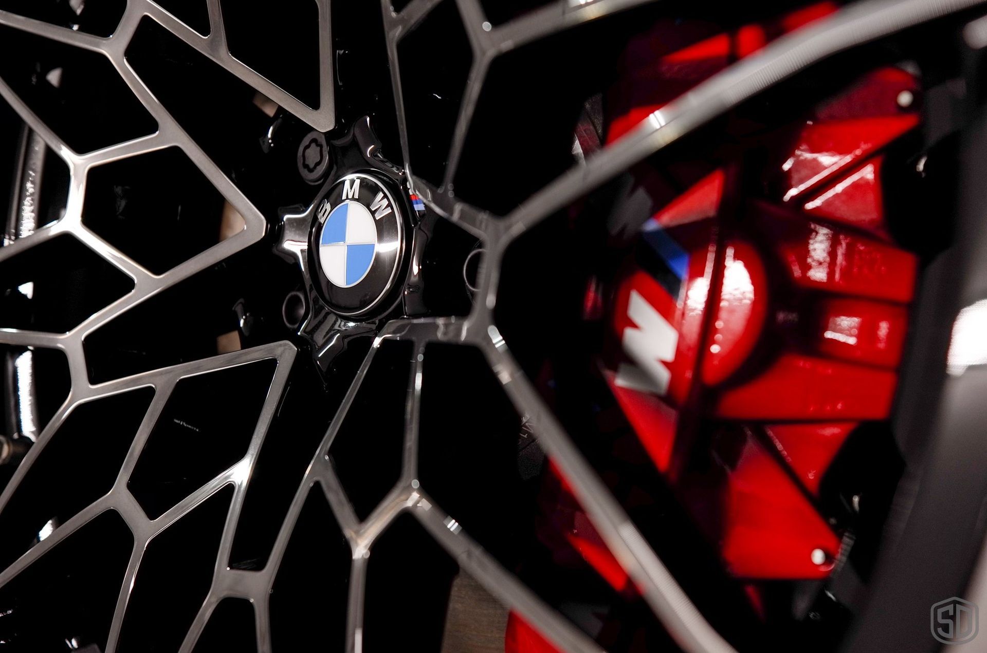 A close up of a bmw wheel with a red brake caliper.