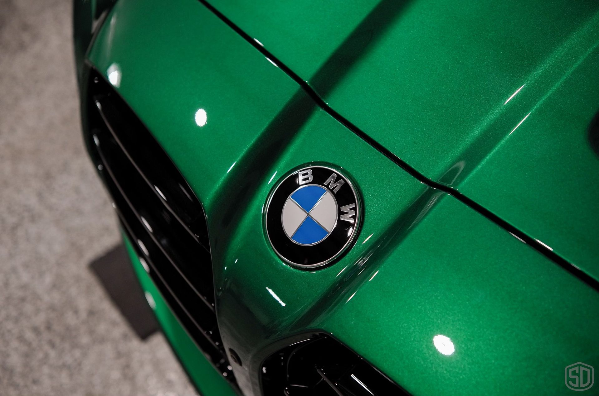 The front of a green bmw with a bmw logo on it.