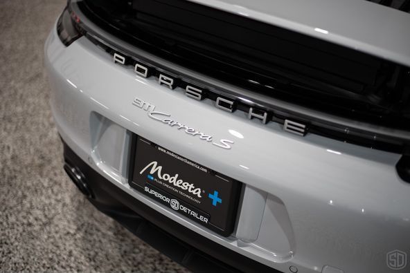 The rear end of a white porsche is shown in a showroom.