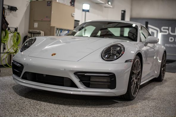 A white porsche 911 is parked in a garage.