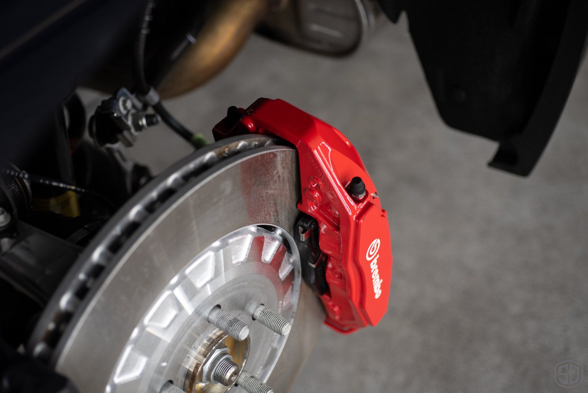 A close up of a red brembo brake caliper on a car.