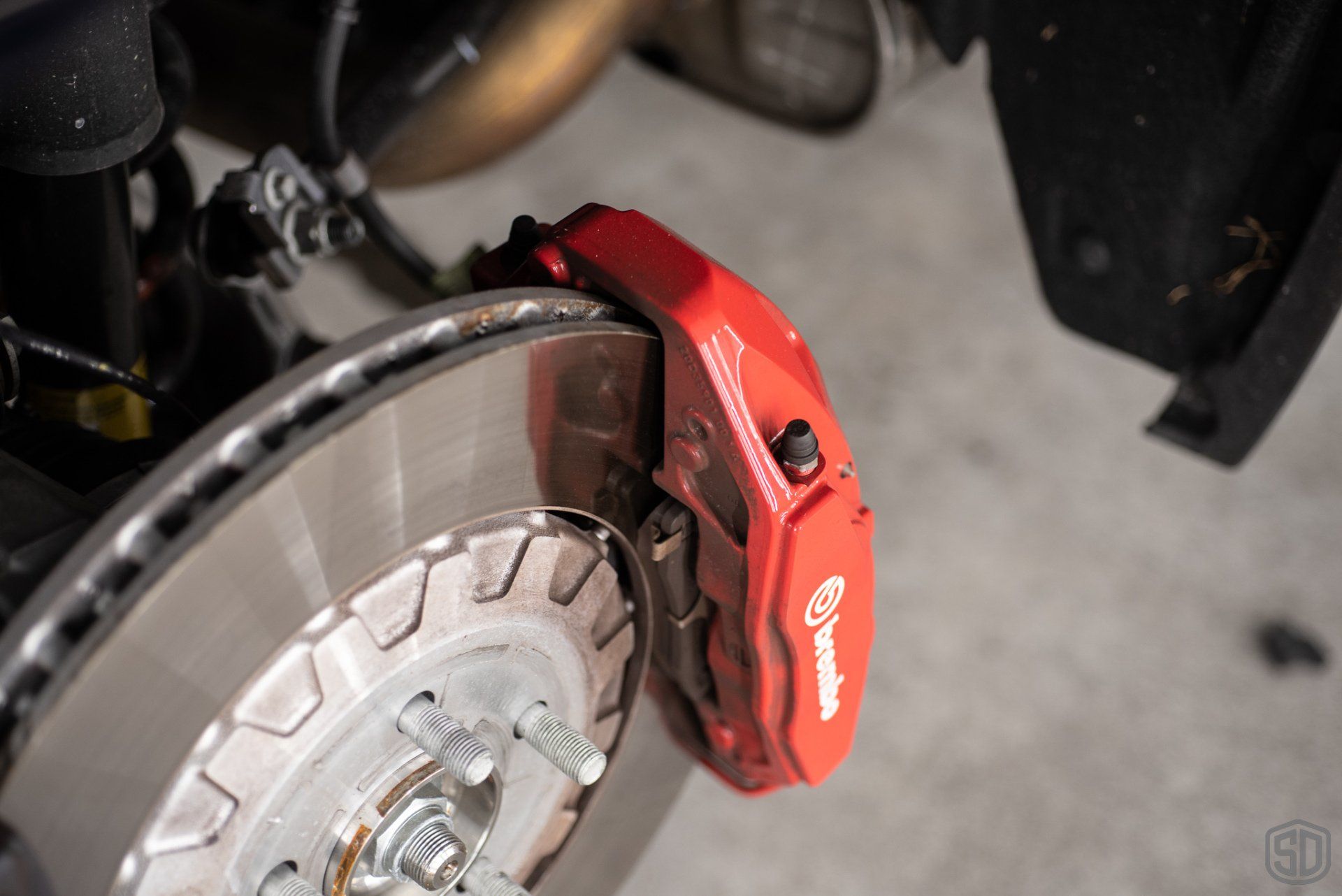 A close up of a red brembo brake caliper on a car.