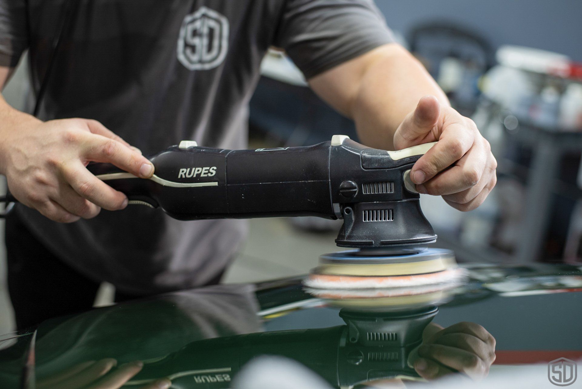 A man is polishing a car with a machine.