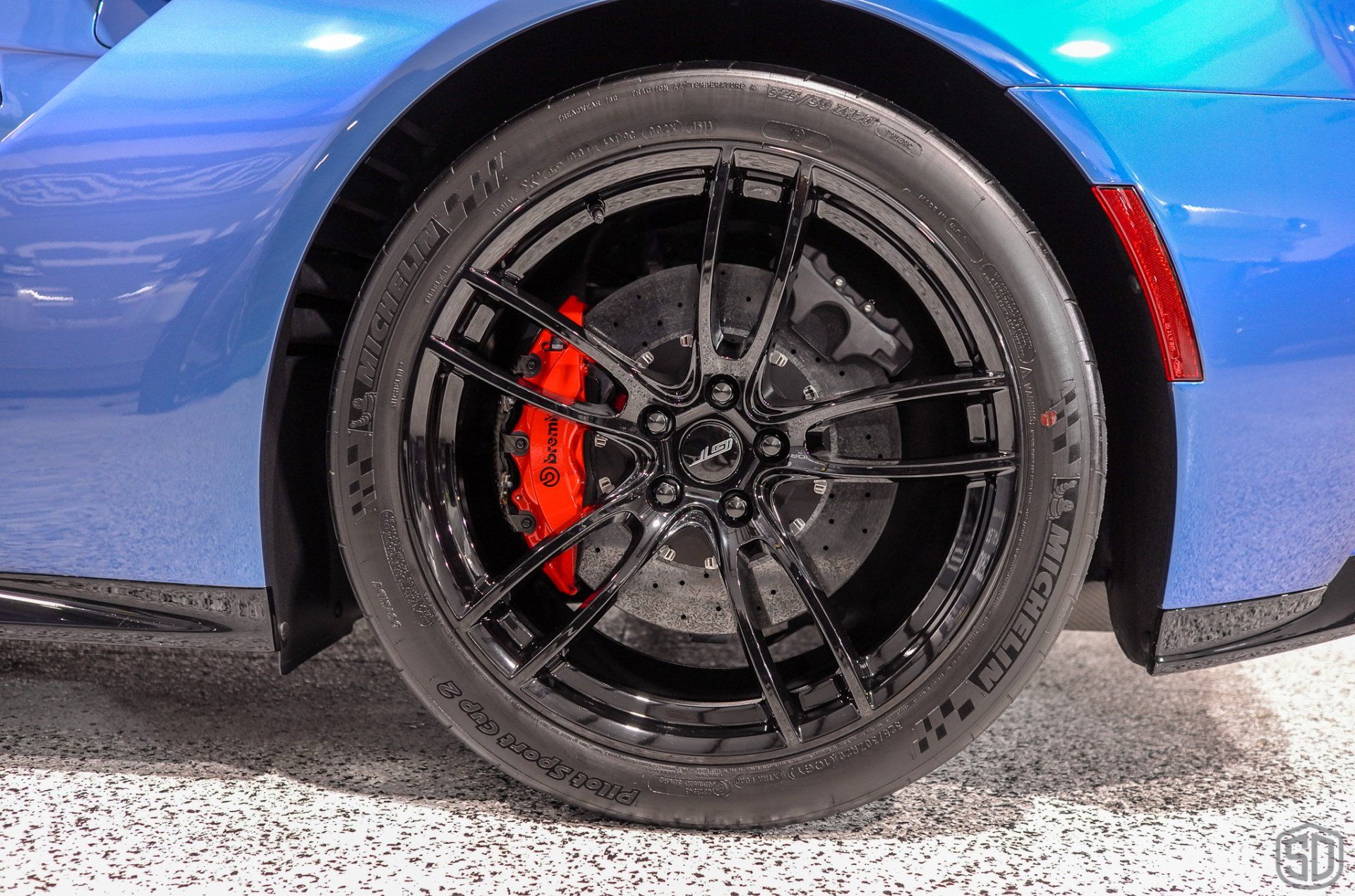A close up of a blue sports car with red brake calipers
