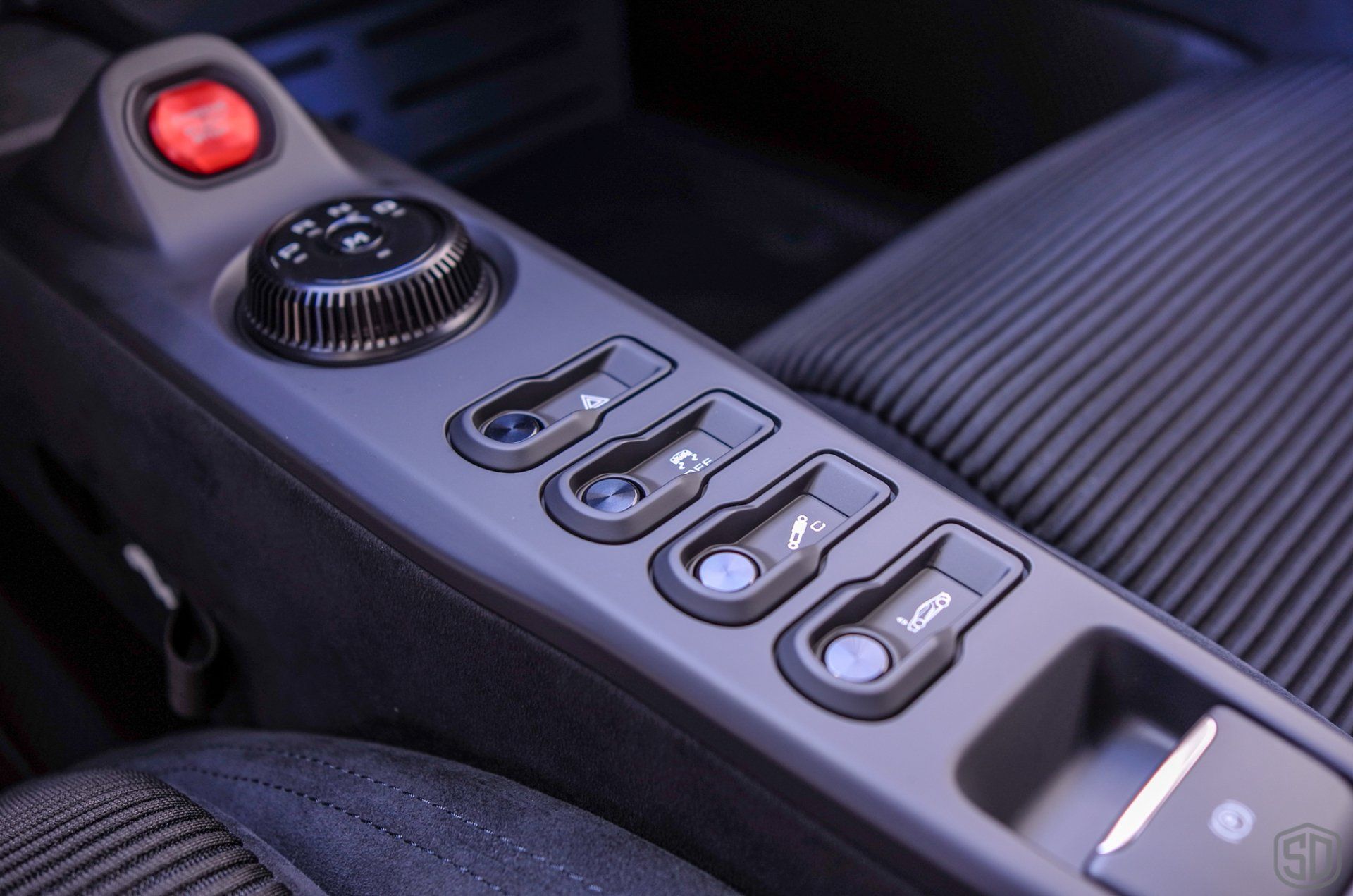 A close up of a car control panel with a red button