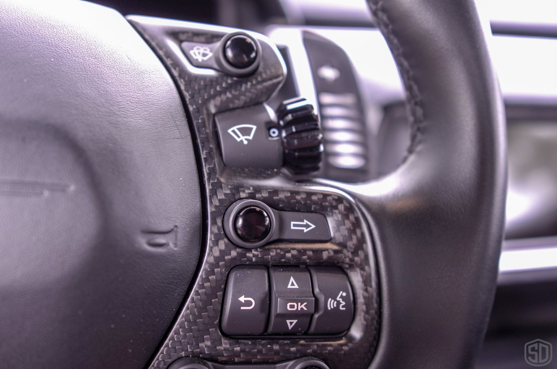 A close up of a car steering wheel with a lot of buttons on it.