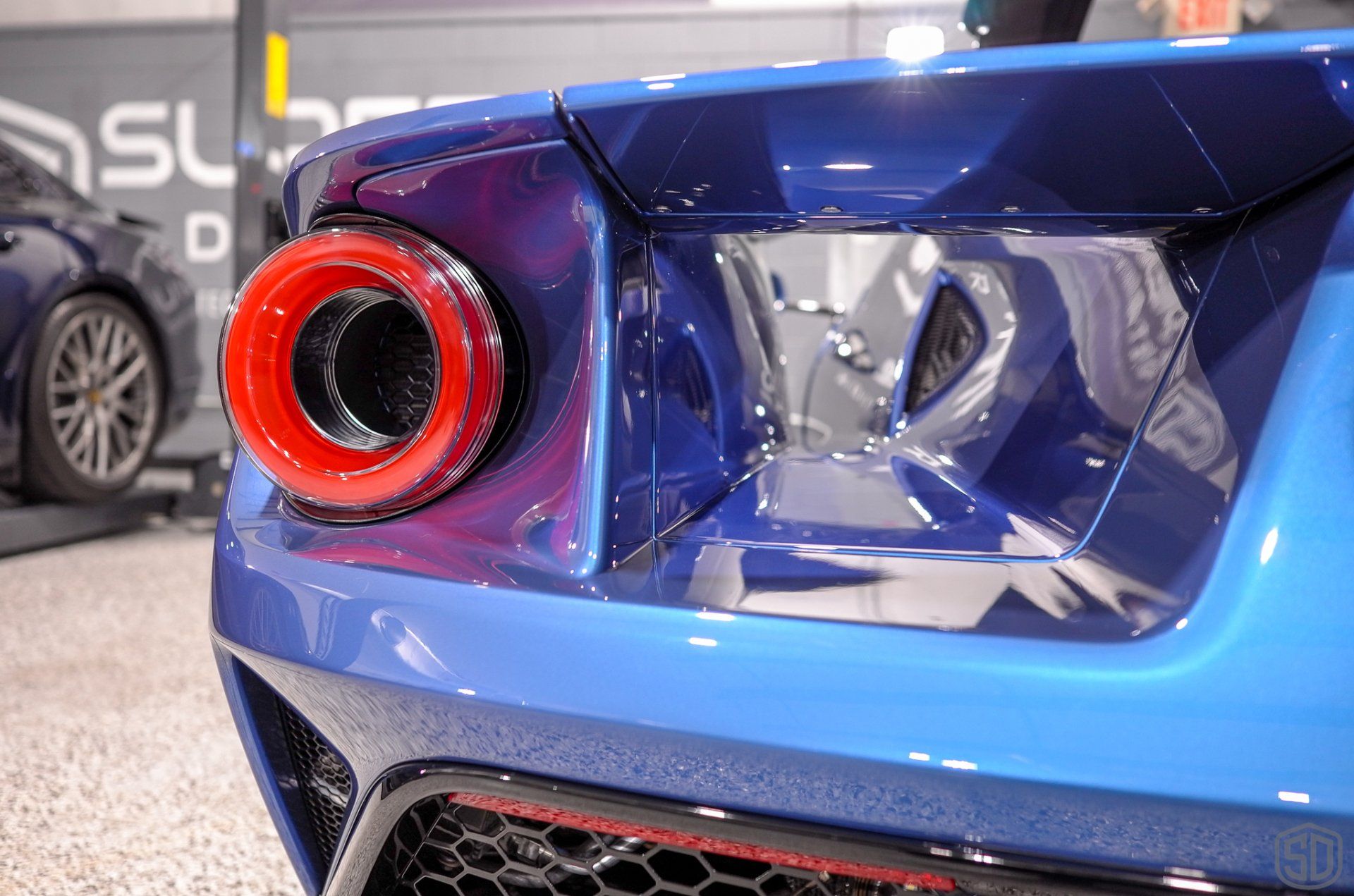 The rear end of a blue sports car with a red tail light.