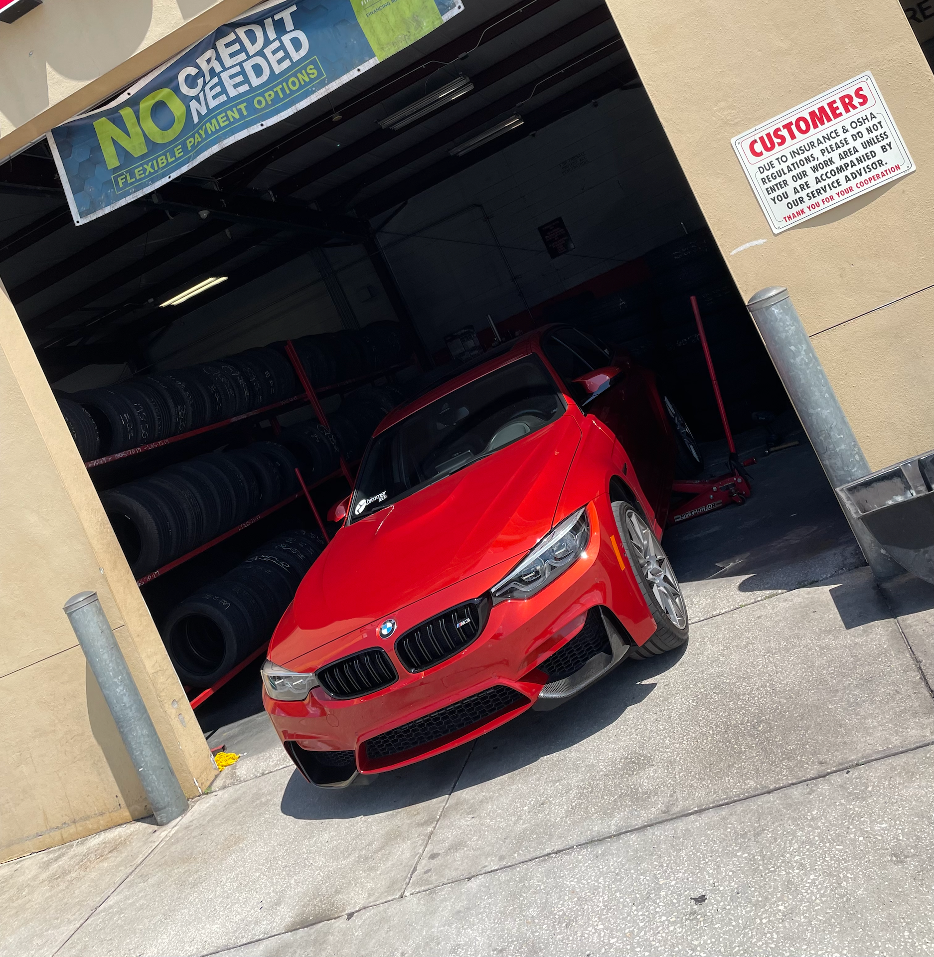 A red car is parked in front of a store that says no credit needed