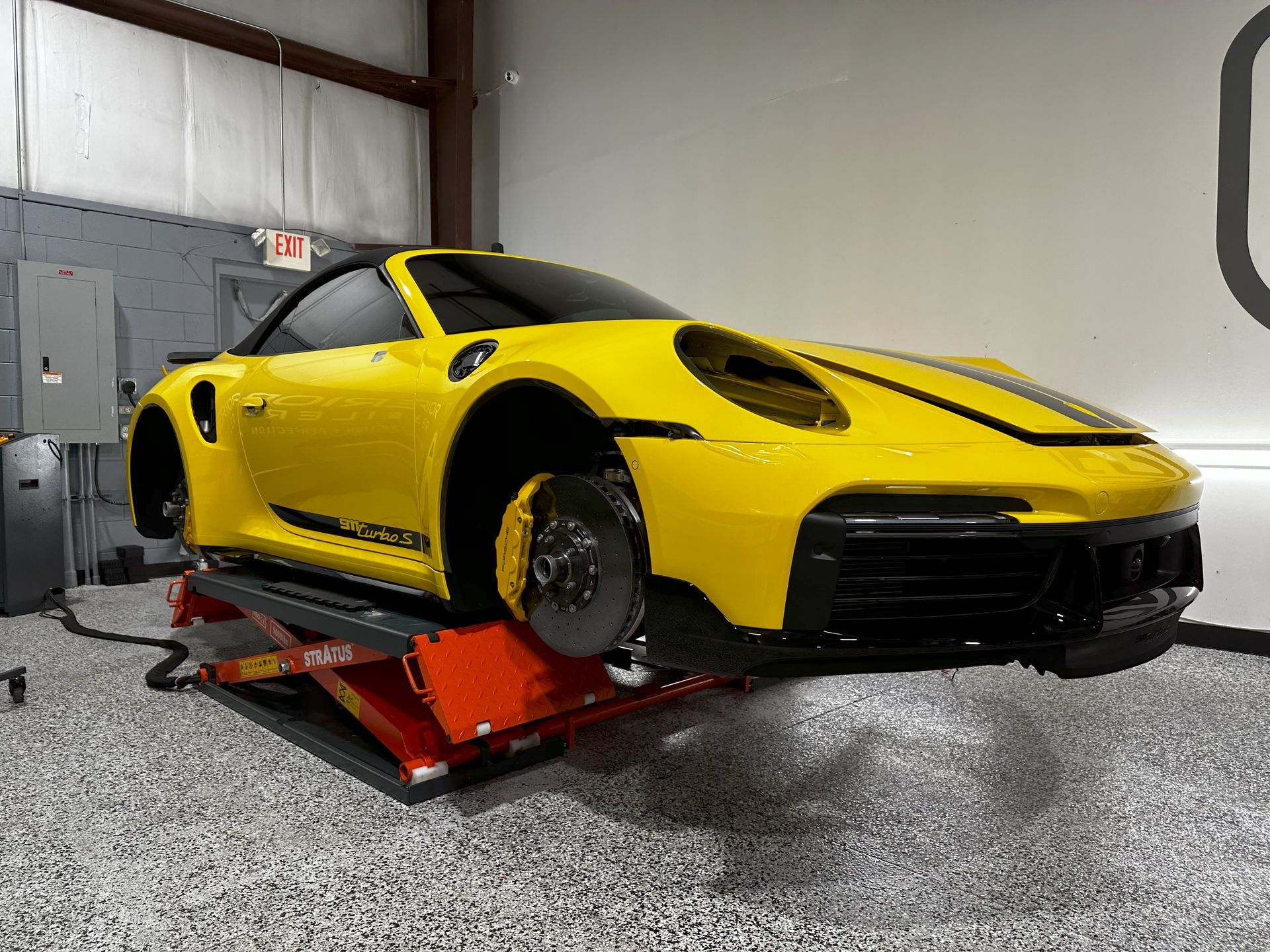 A yellow sports car is sitting on a lift in a garage.