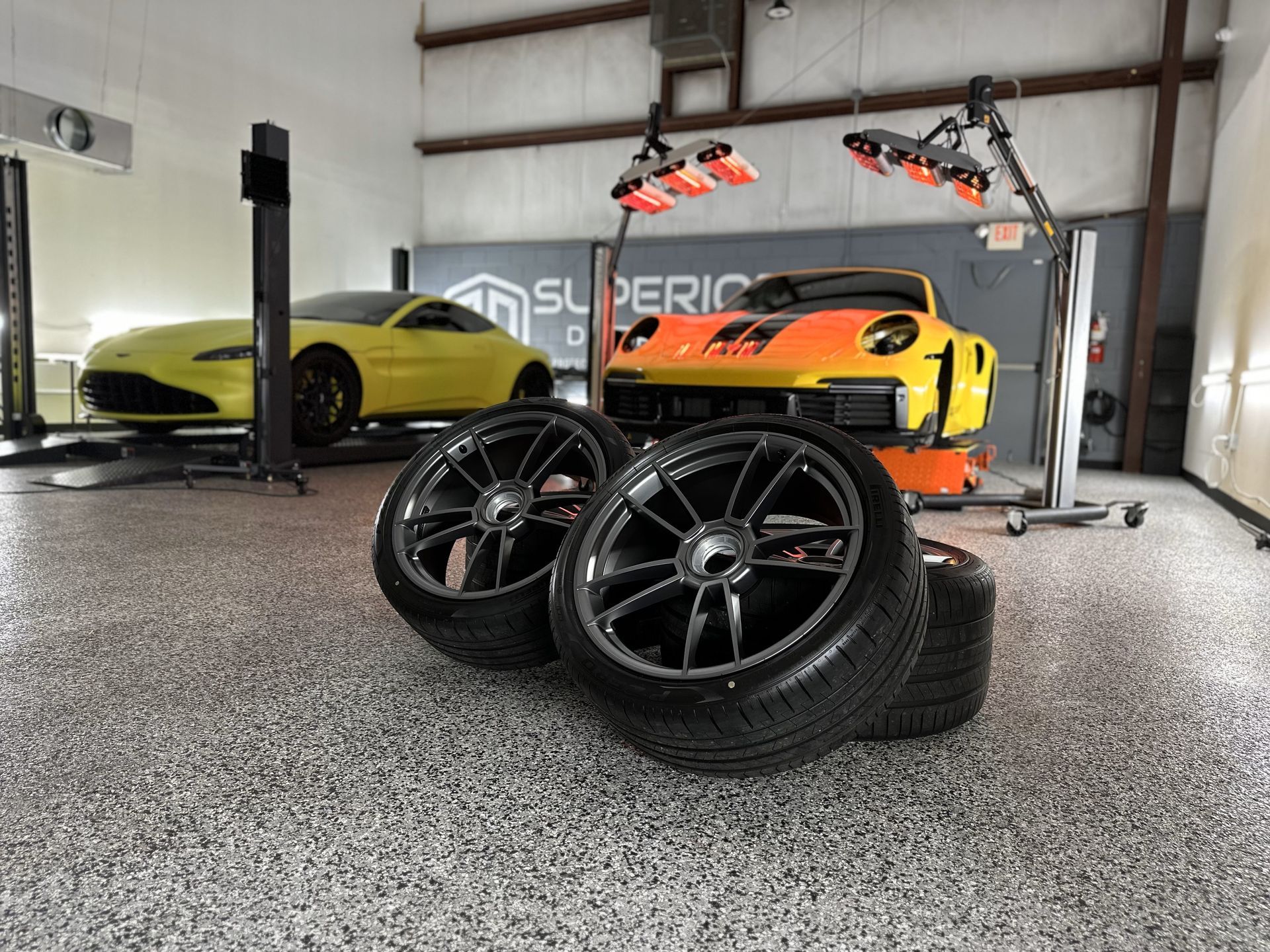 A yellow car is parked in a garage next to a pile of tires.