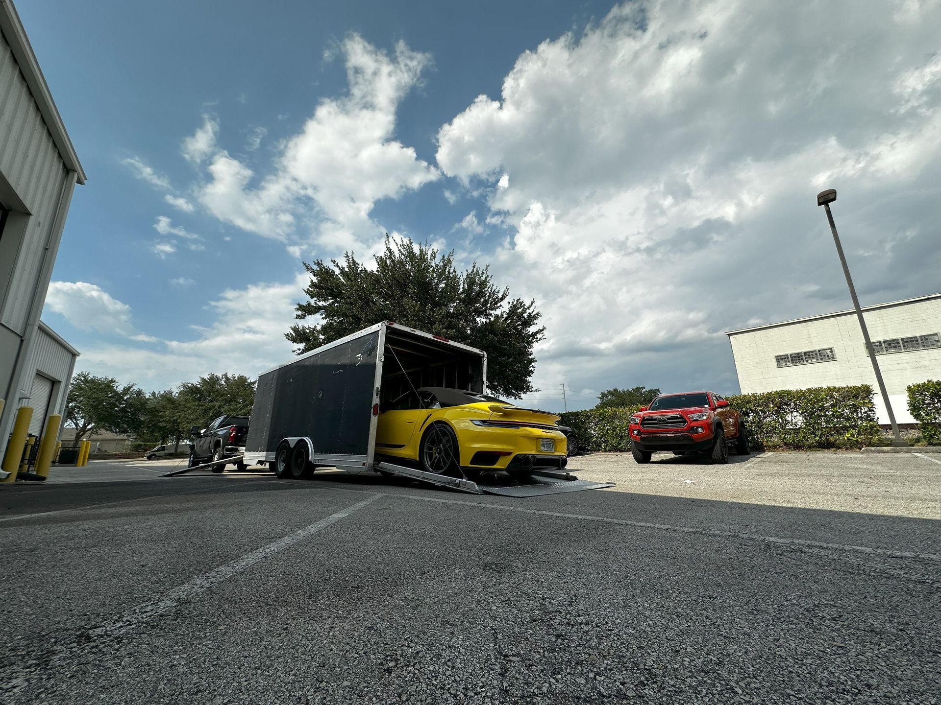 A yellow sports car is being towed by a trailer.